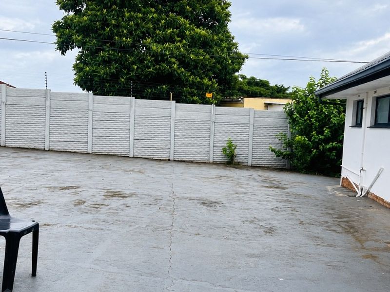 A rear exterior area featuring a large concrete paved yard enclosed by a precast concrete wall with electric fencing.