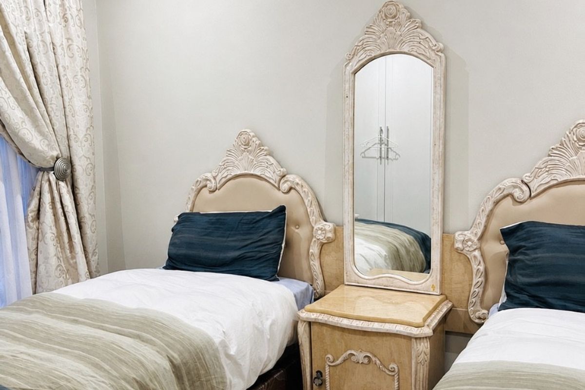A well-maintained bedroom featuring neutral wall tones, recessed downlighting, and laminate flooring, providing a comfortable and functional guest accommodation space.
