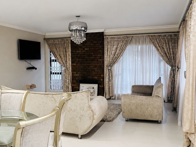 A well-maintained living room featuring an exposed brick fireplace, tiled flooring, and recessed lighting, creating a comfortable and inviting atmosphere.