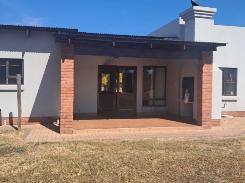 A covered patio area featuring brick pillars, tiled flooring, and a built-in braai, providing a functional outdoor space for entertaining.