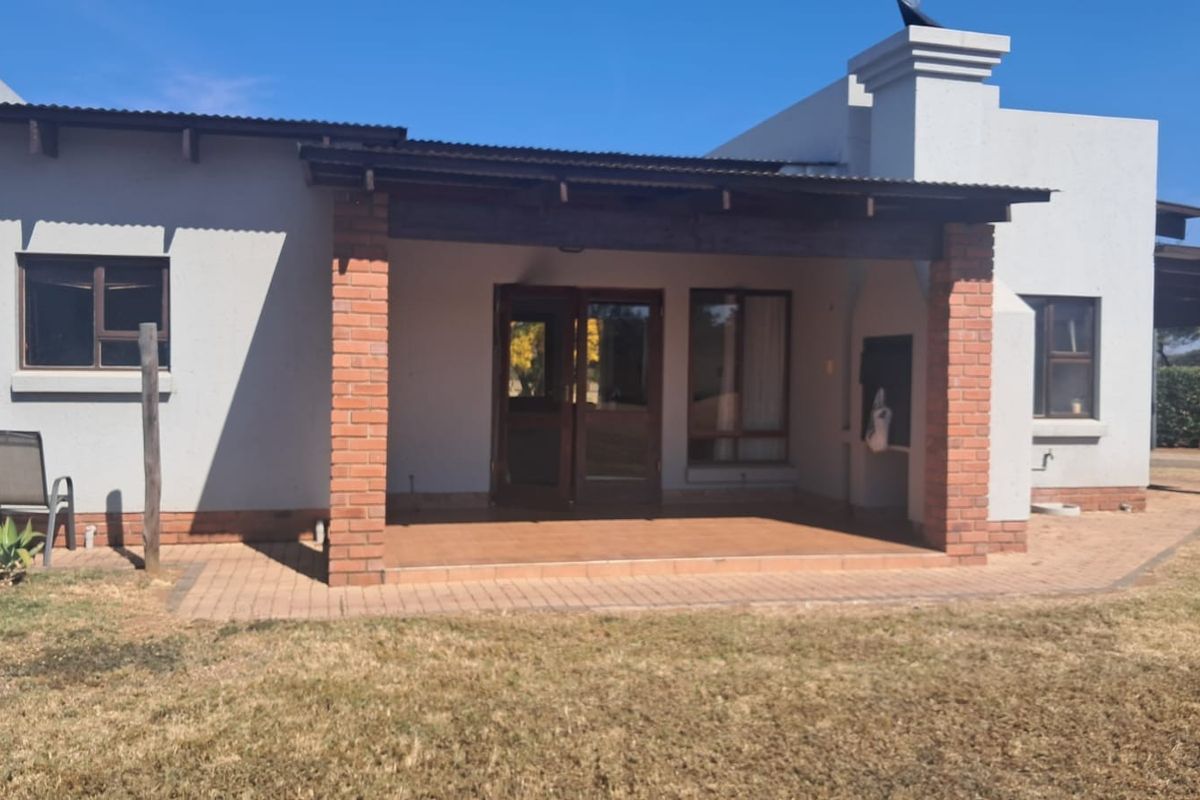 A covered patio area featuring brick pillars, tiled flooring, and a built-in braai, providing a functional outdoor space for entertaining.