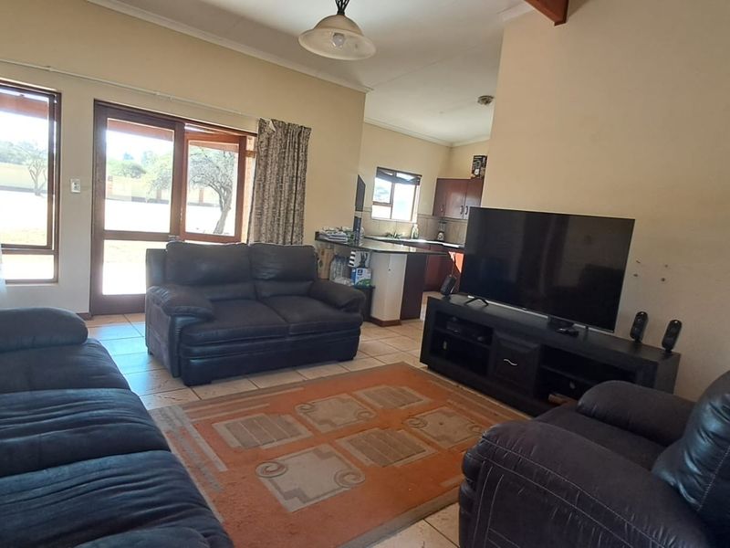 Open plan living area featuring tiled flooring, a breakfast bar connecting to the kitchen, and sliding glass doors leading to the exterior.