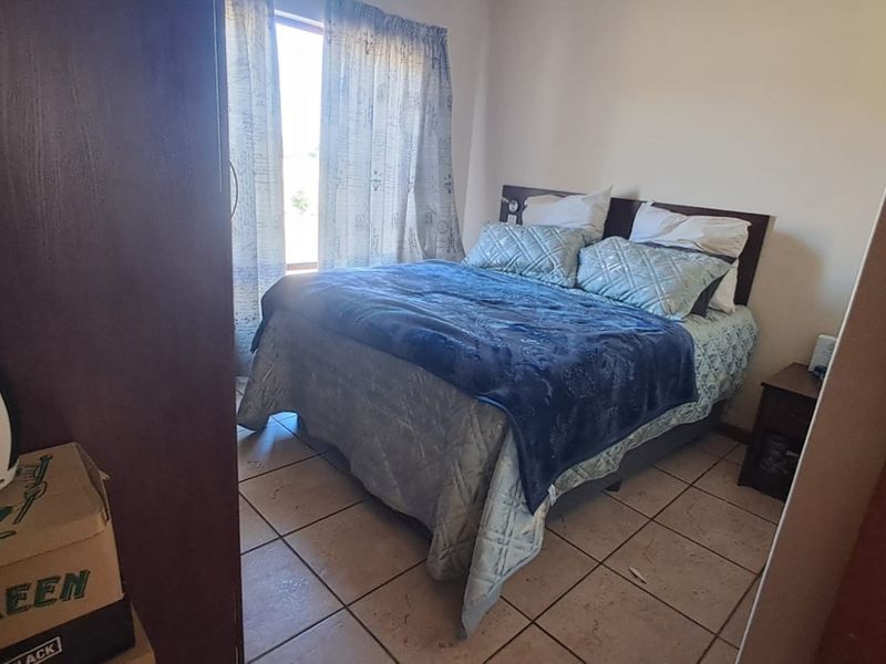 A functional bedroom featuring tiled flooring and a built-in cupboard, providing a practical and comfortable sleeping space.