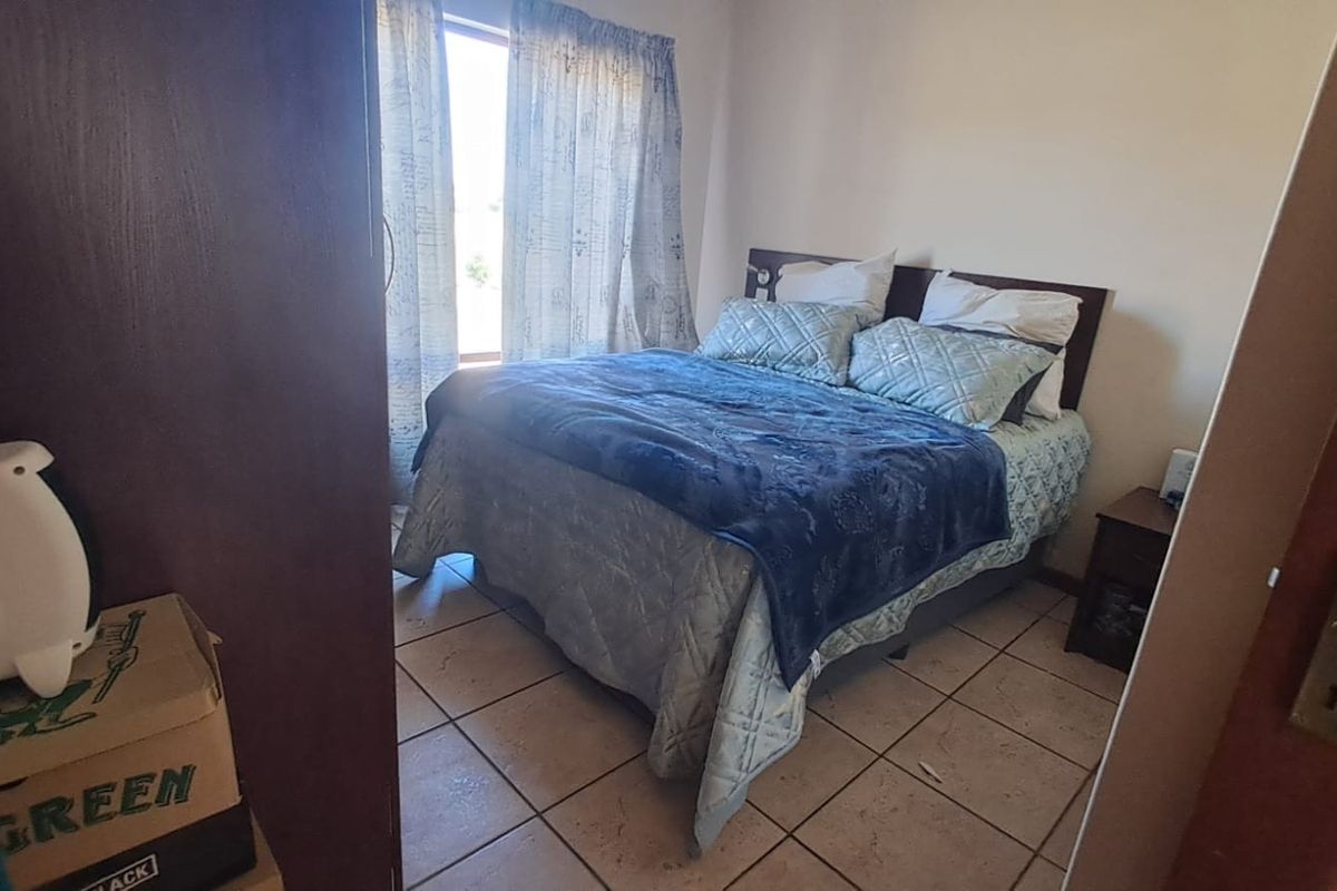 A functional bedroom featuring tiled flooring and a built-in cupboard, providing a practical and comfortable sleeping space.