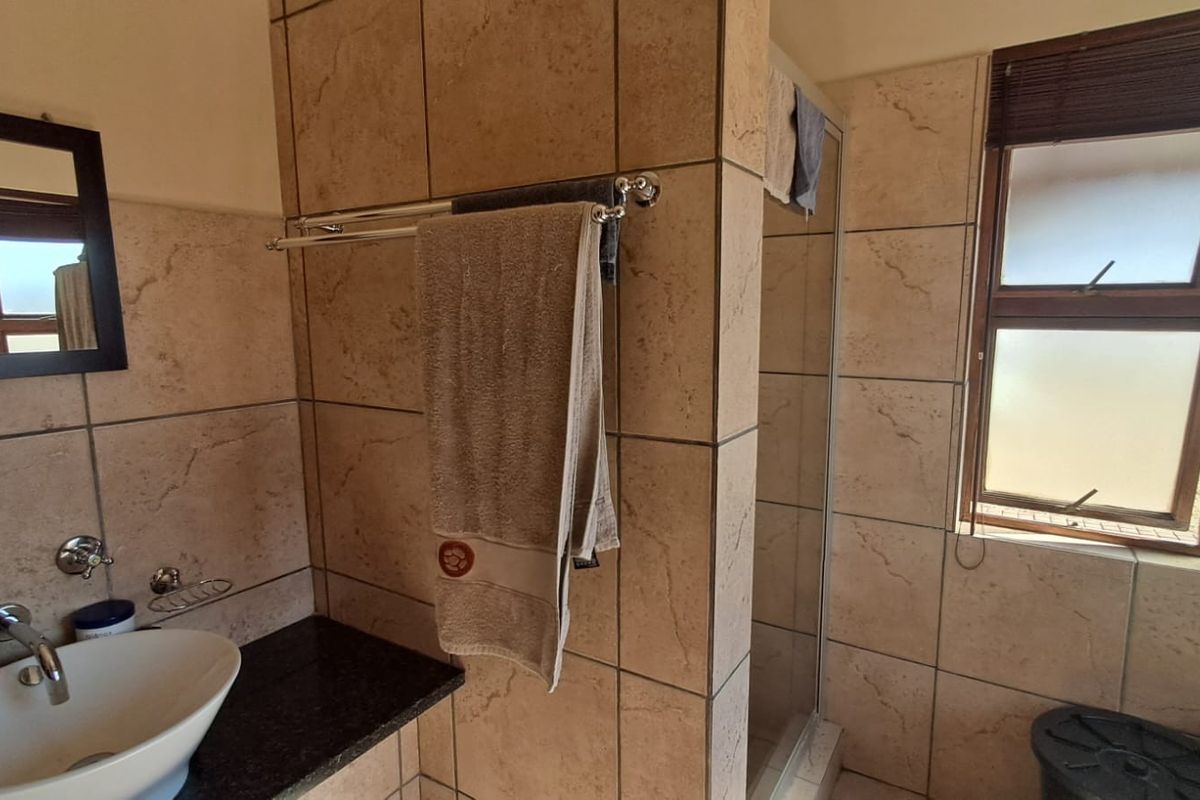 A functional bathroom featuring a vessel sink on a granite vanity, tiled walls, and a separate shower enclosure with natural light.