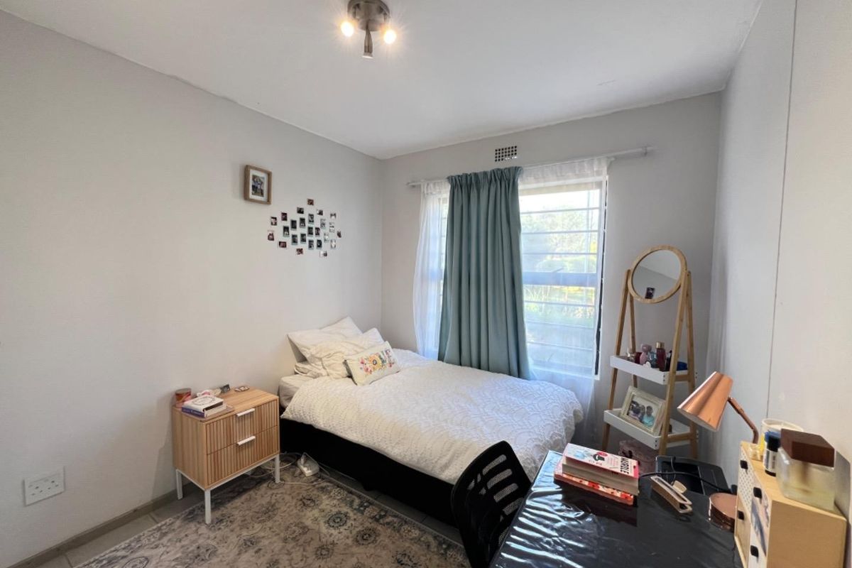A functional bedroom featuring neutral wall finishes, a window with curtain hardware, and a ceiling light fixture.