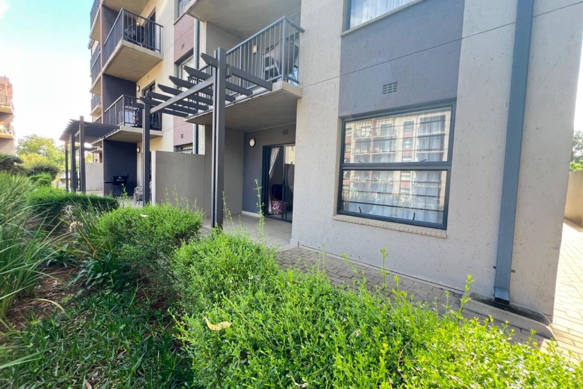 Ground floor apartment exterior featuring a private paved patio, pergola, and direct access to the landscaped garden area.