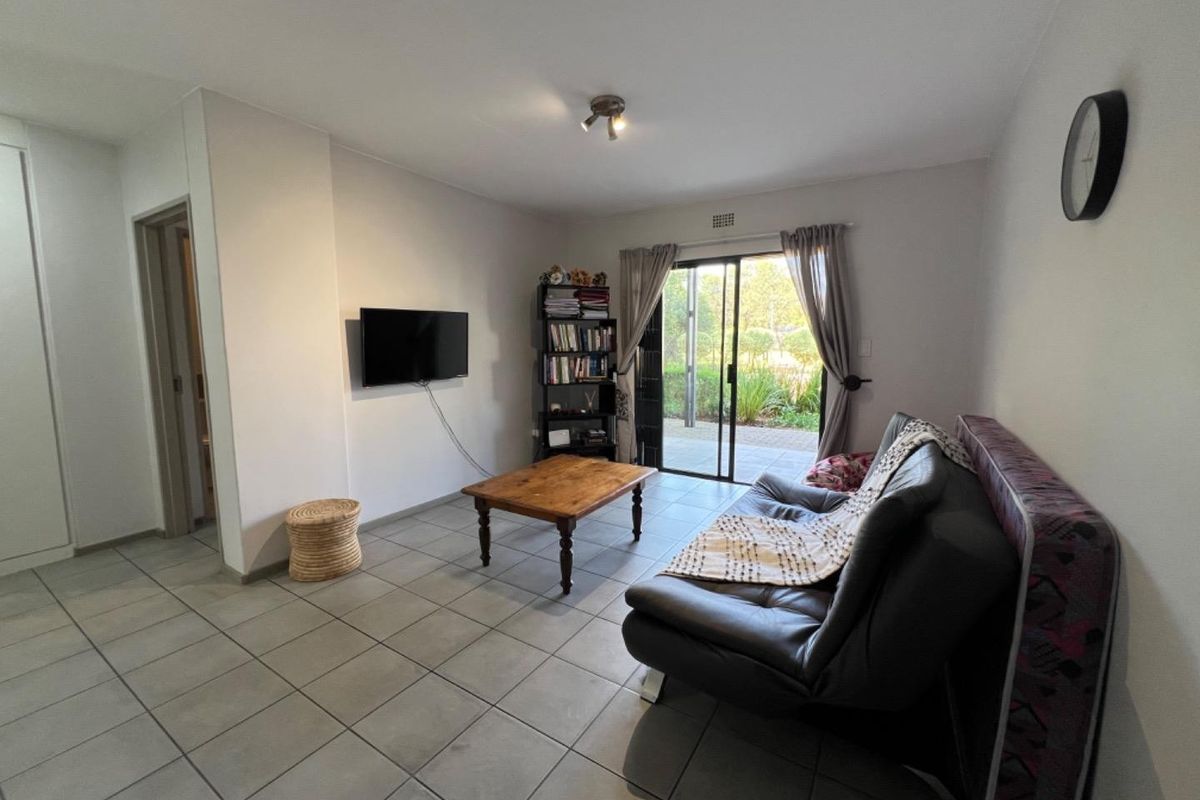 A living room featuring neutral tiled flooring and a sliding glass door providing direct access to the outdoor area.