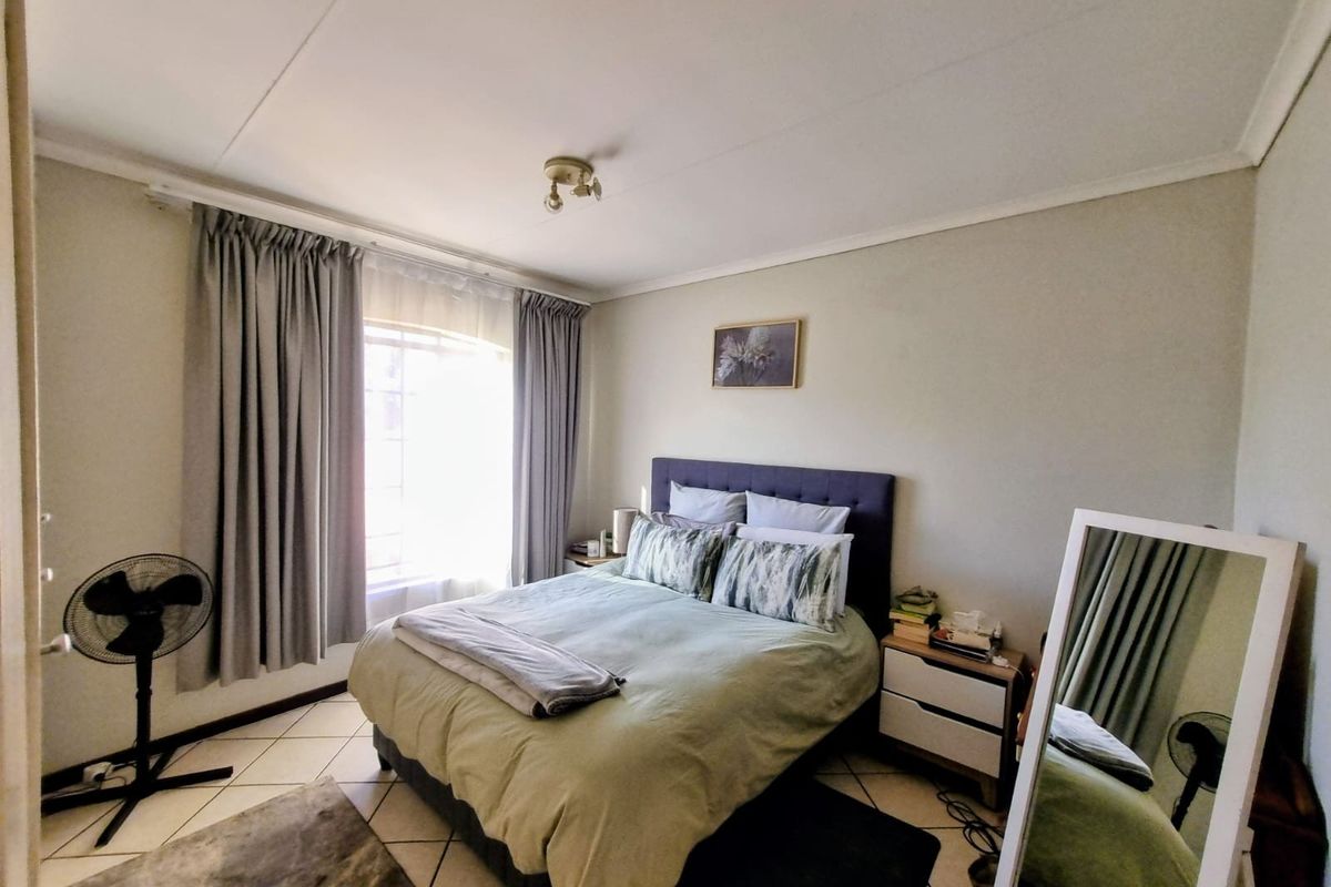 A functional bedroom featuring tiled flooring, neutral wall finishes, and natural light provided by a window with installed curtain tracks.