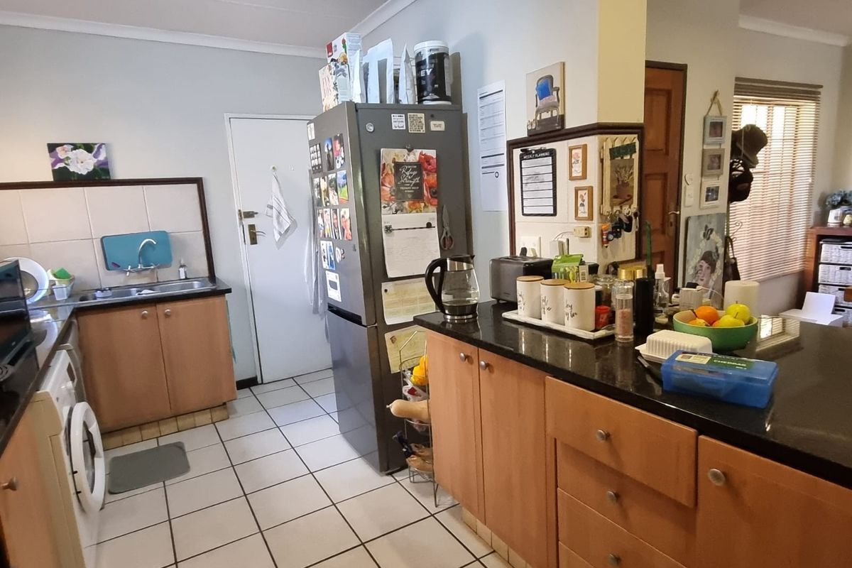 Functional kitchen featuring laminate cabinetry, granite countertops, tiled flooring, and integrated laundry plumbing, offering a practical layout for daily meal preparation.