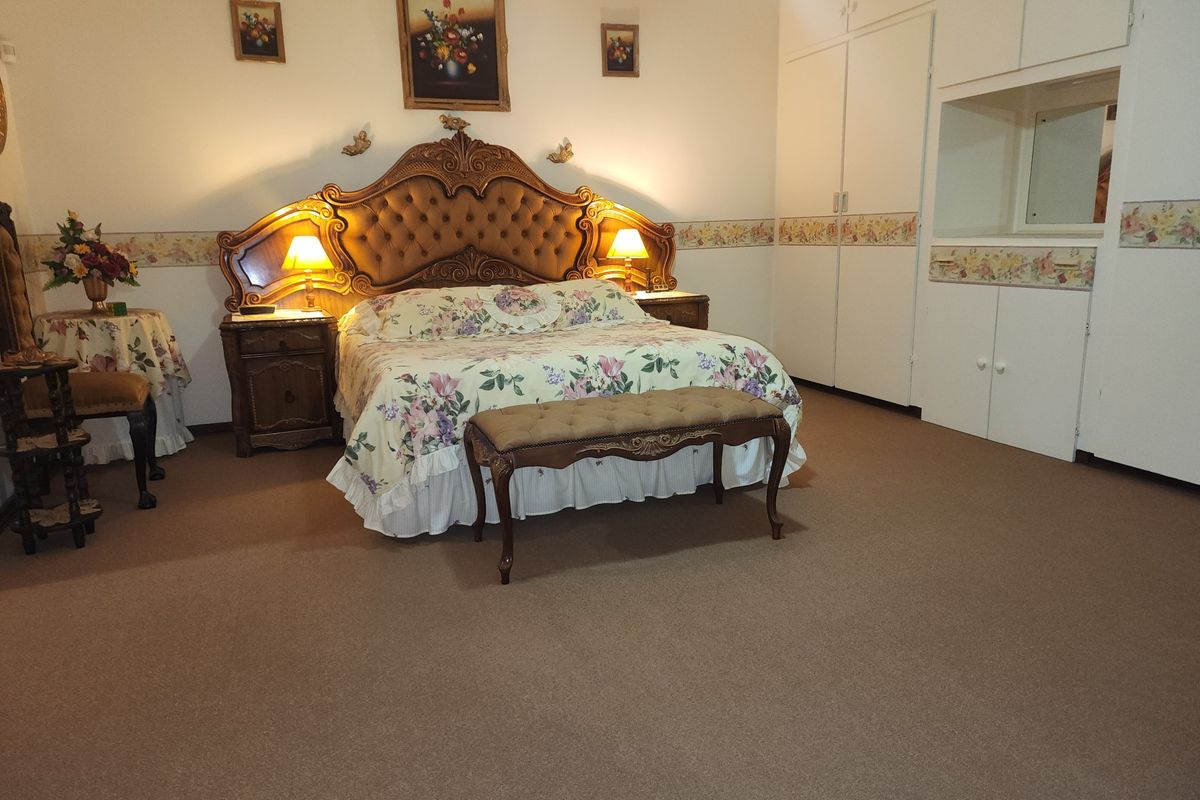 Spacious bedroom featuring neutral carpet flooring, extensive built-in wardrobe storage, and decorative coving.