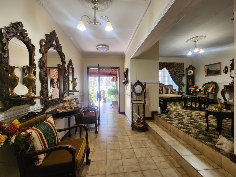 An inviting entrance hall featuring tiled flooring, decorative ceiling roses, and coving, leading into a raised living area with a traditional aesthetic.