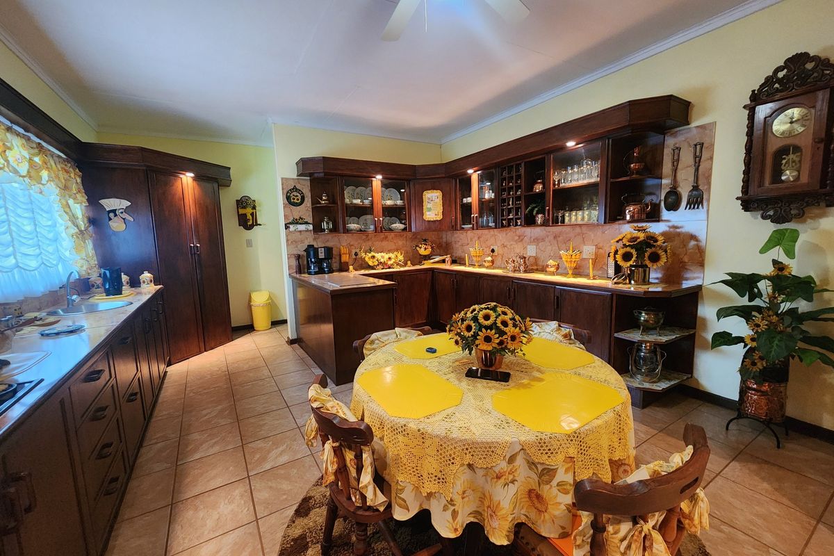 A spacious kitchen featuring dark wood cabinetry, tiled flooring, and a dedicated dining area with ample counter space and integrated storage.
