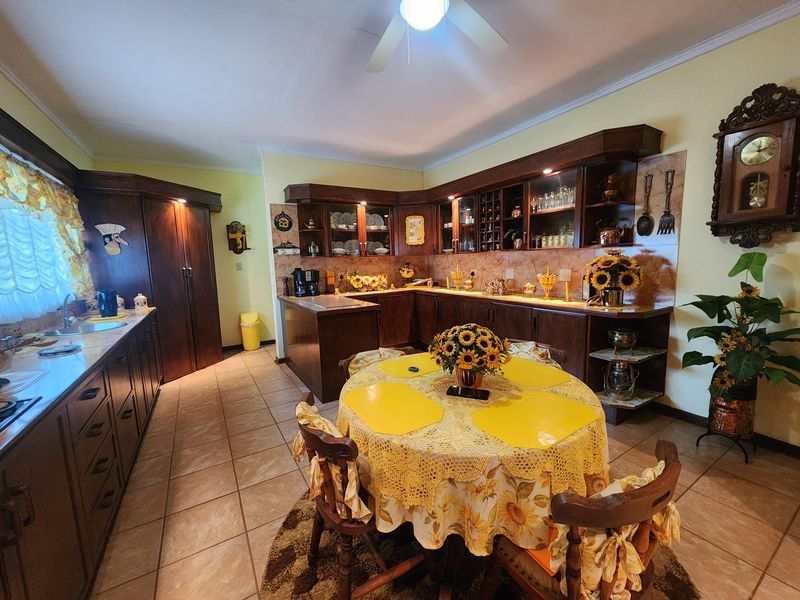 A spacious kitchen featuring dark wood cabinetry, tiled flooring, and a dedicated dining area with ample counter space and integrated storage.