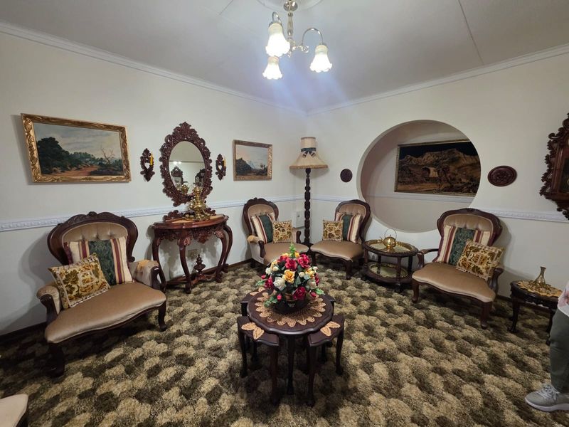 A traditional living room featuring a circular wall niche, decorative molding, and carpeted flooring, offering a classic aesthetic with potential for modern updates.