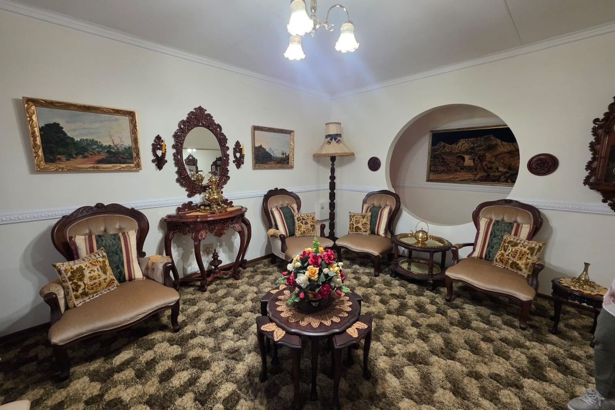 A traditional living room featuring a circular wall niche, decorative molding, and carpeted flooring, offering a classic aesthetic with potential for modern updates.