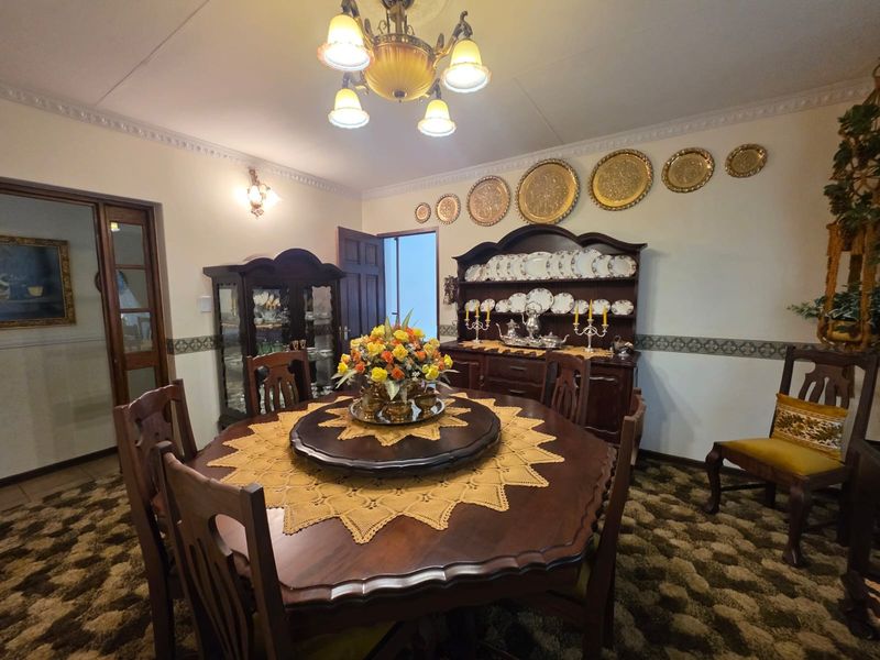 A traditional dining room featuring decorative ceiling cornicing, a central chandelier, and timber door frames, offering a classic layout for formal entertaining.
