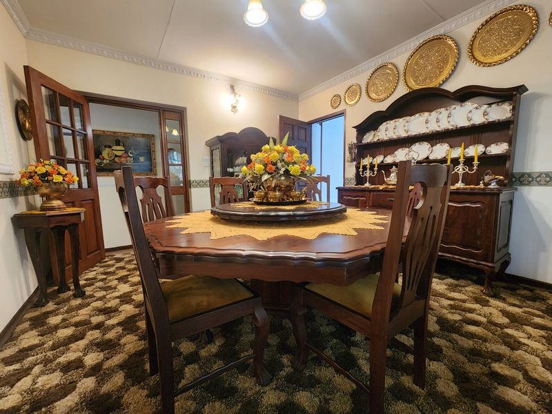 A formal dining room featuring crown molding, classic wall sconces, and traditional wooden french doors, offering a structured space for family meals.