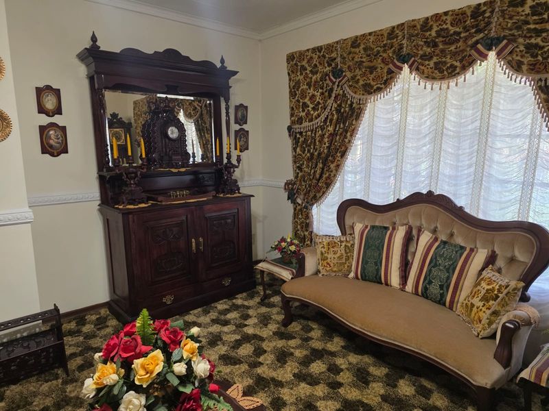 A traditional living room featuring decorative wall molding and coving, currently styled with vintage finishes and patterned carpeting.