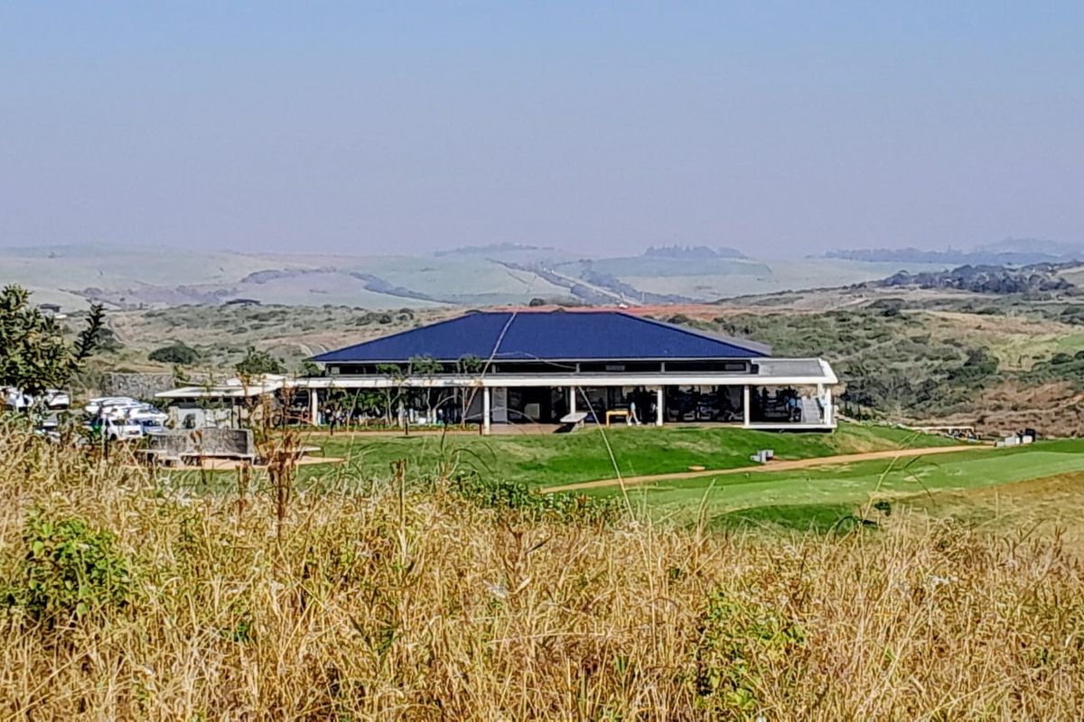 A scenic elevated view overlooking a golf course and the clubhouse facility set within a rolling landscape.