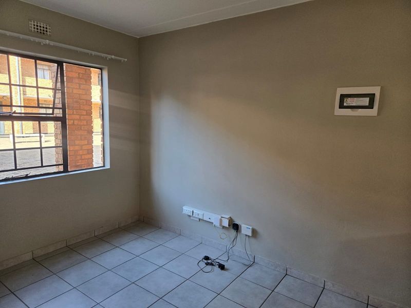 An empty bedroom featuring neutral wall paint, tiled flooring, and a steel-framed window with security bars.