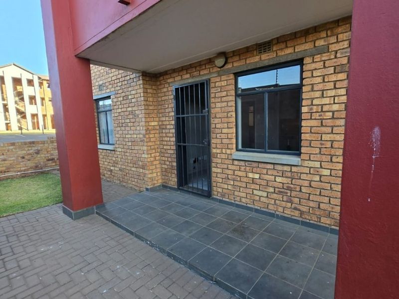A ground floor patio area featuring brick exterior walls, tiled flooring, and secure access points with metal security gates and window bars.