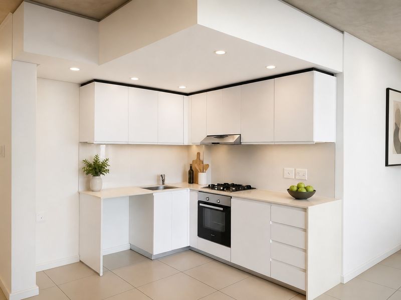 Modern, compact kitchen featuring white cabinetry, integrated gas hob, built-in oven, extractor fan, and neutral tiled flooring with recessed lighting.