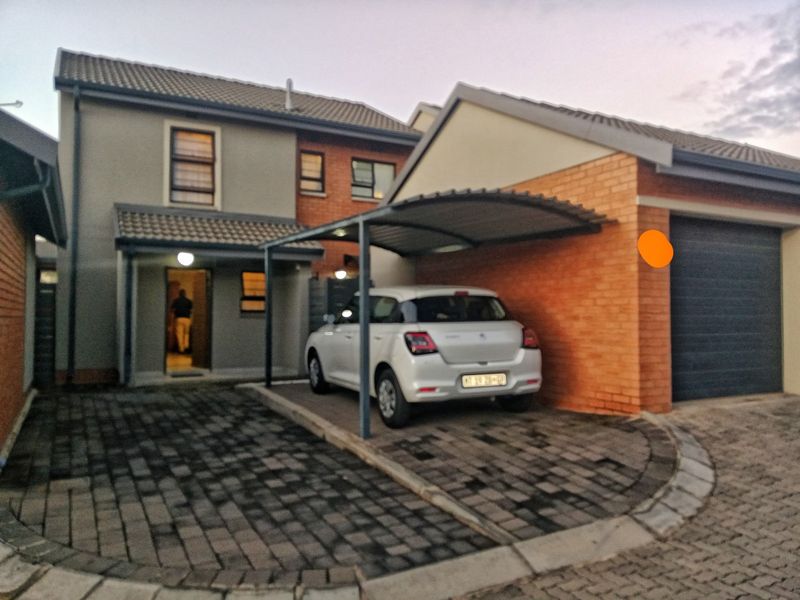 Front elevation of a two-story house featuring a paved driveway, a covered carport, and an integrated garage.
