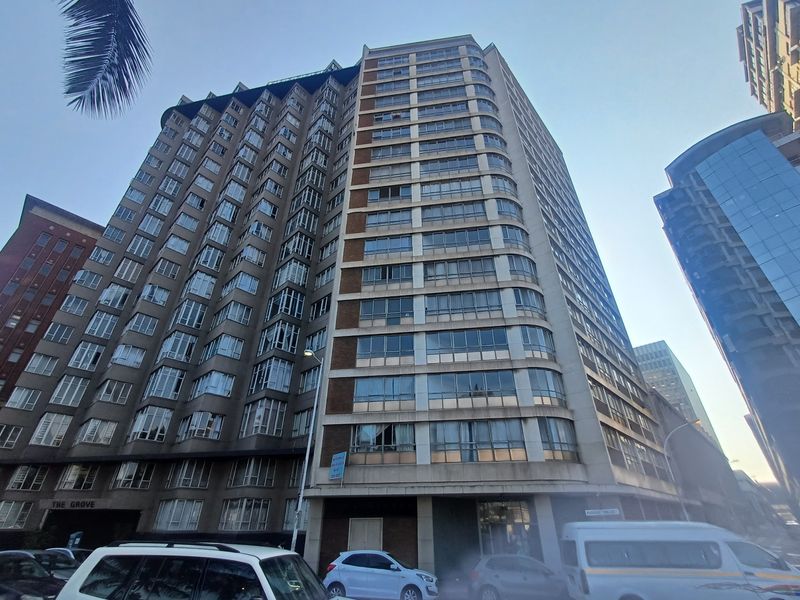 A low-angle exterior view of a large, multi-story apartment building featuring a concrete facade and extensive window glazing.