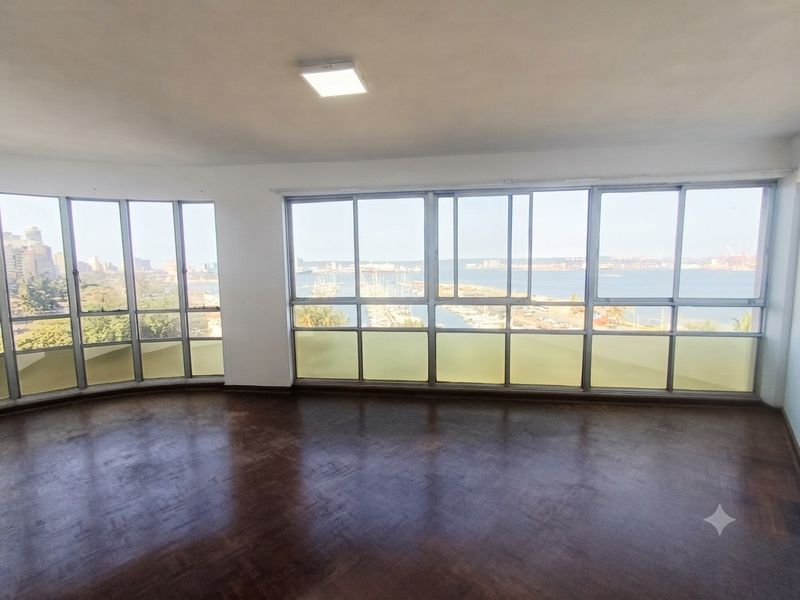 Spacious living area featuring original parquet flooring and expansive windows offering panoramic harbour and city views.