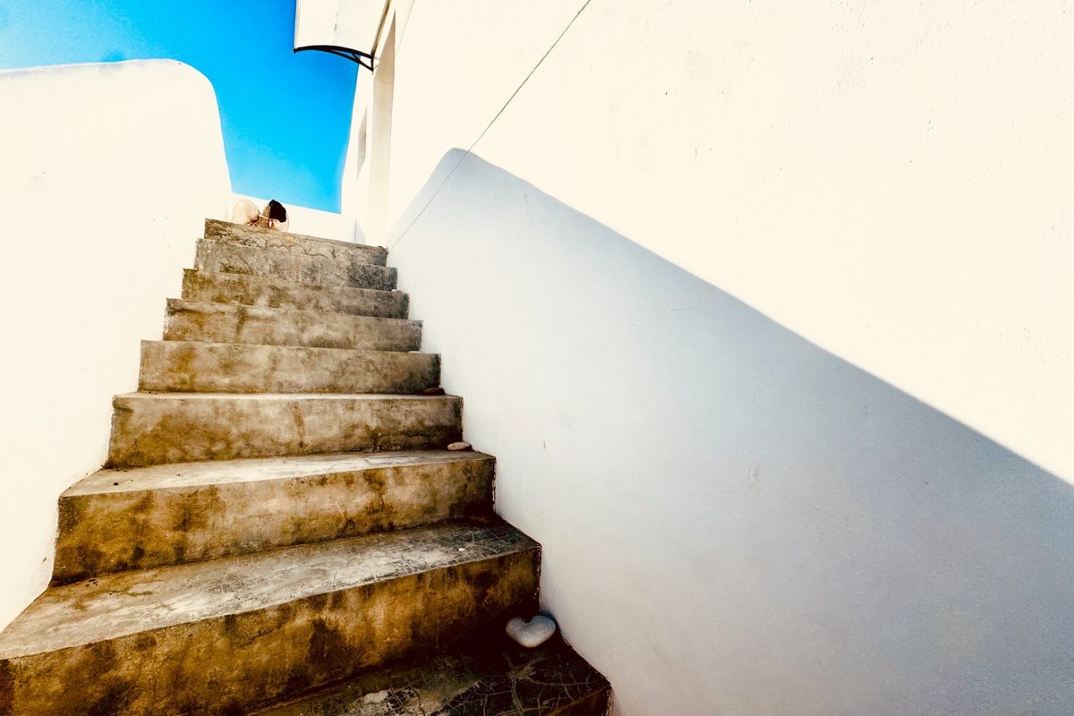 An exterior concrete staircase leading upwards, featuring weathered steps and plain white walls.