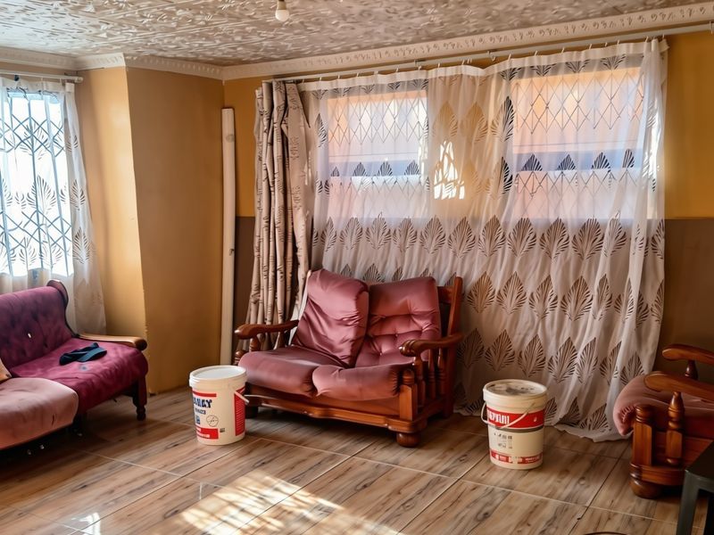 Living room featuring wood-look floor tiles and a decorative pressed metal ceiling, offering a dated aesthetic with potential for modernization.