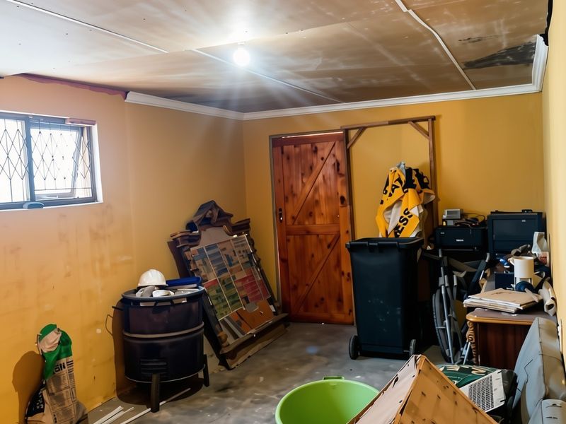 Utility space featuring a timber door, security window, and unfinished ceiling panels requiring repair and cosmetic updates.