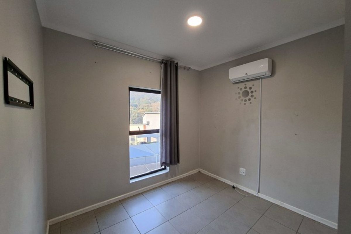 A clean, empty bedroom featuring tiled flooring, an installed air conditioning unit, and neutral wall finishes, ready for personalization.
