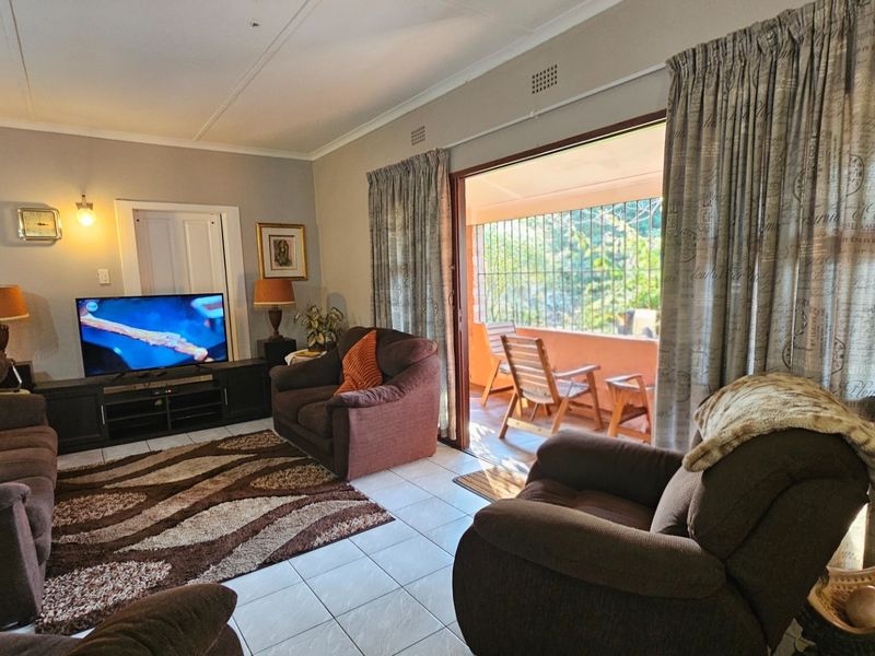 A comfortable living room featuring tiled flooring and a large sliding glass door that provides direct access to an outdoor patio area.