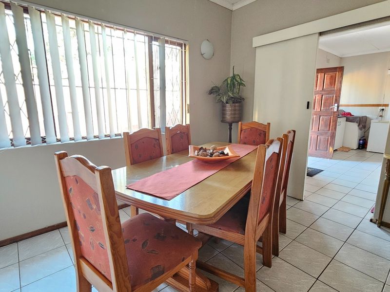 Dining room featuring tiled flooring, vertical blinds with security bars, and a sliding door providing access to the adjacent room.