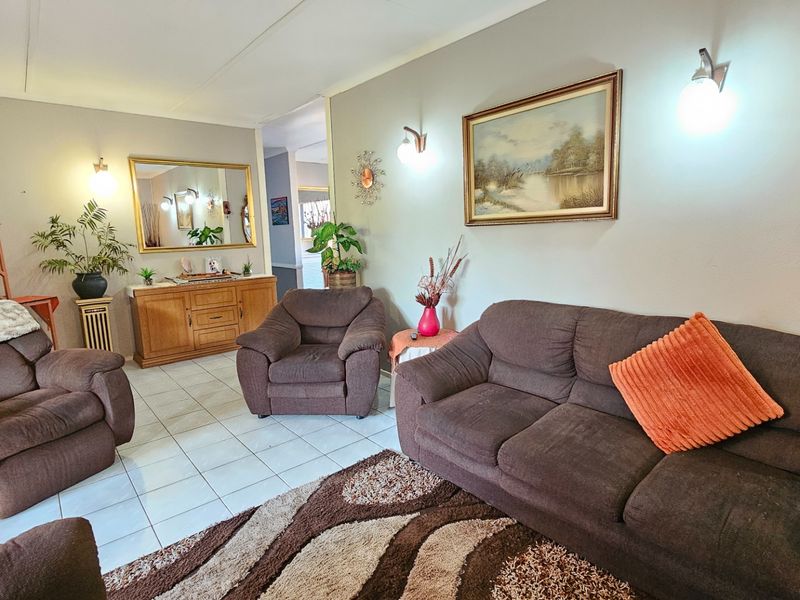 A living room featuring tiled flooring and wall-mounted lighting, providing a functional and neutral space for relaxation.