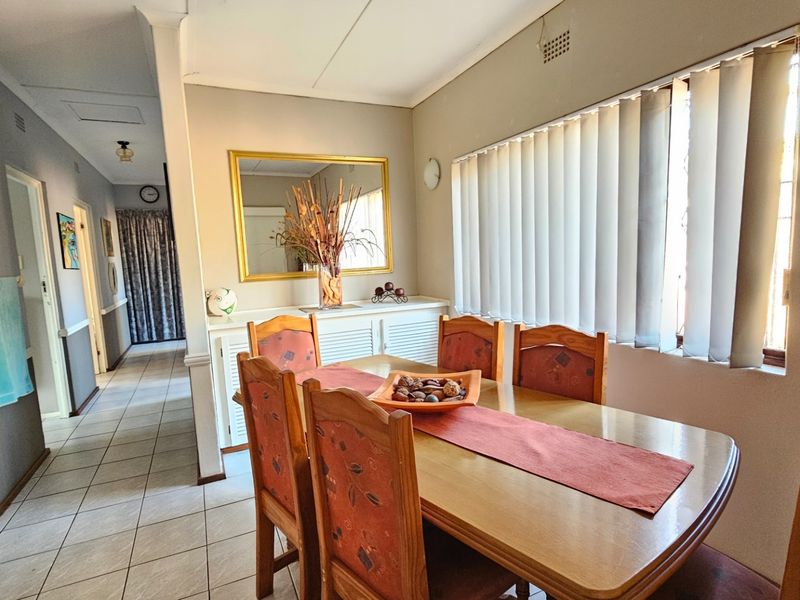 A dining area featuring tiled flooring, built-in cabinetry, and vertical blinds, providing a functional space with direct access to the hallway.