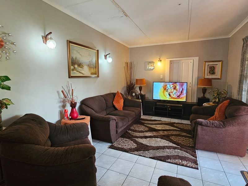 A living room featuring tiled flooring and wall-mounted lighting, with visible damage to the ceiling panels requiring repair.