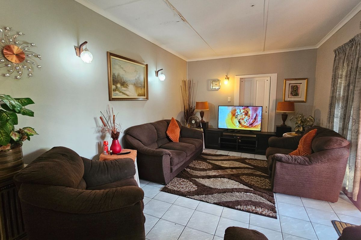 A living room featuring tiled flooring and wall-mounted lighting, with visible damage to the ceiling panels requiring repair.