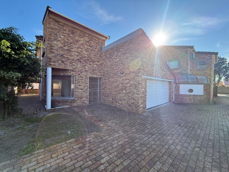 Front exterior view of a face brick house featuring a paved driveway, garage, and secure entrance area.