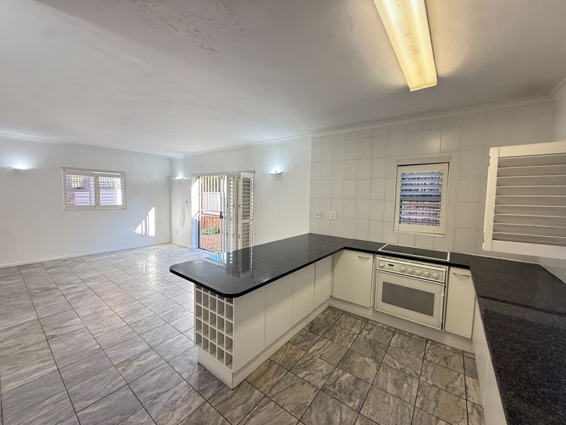 Spacious open-plan kitchen and living area featuring granite countertops, built-in oven, electric hob, and tiled flooring throughout.