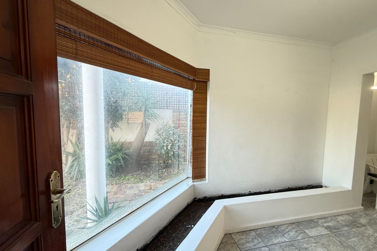 An empty living area featuring tiled flooring, a large bay window, and a built-in internal planter box.