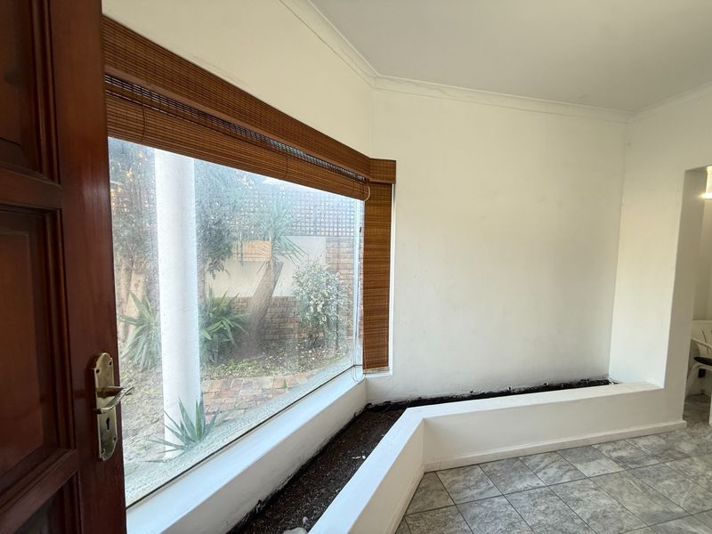 An empty living area featuring tiled flooring, a large bay window, and a built-in internal planter box.