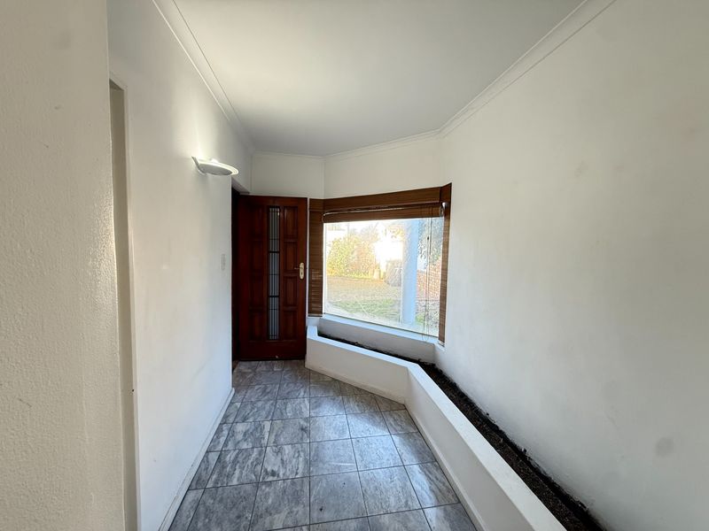 An entrance hall featuring tiled flooring, a built-in planter box under a large window, and a solid timber front door.