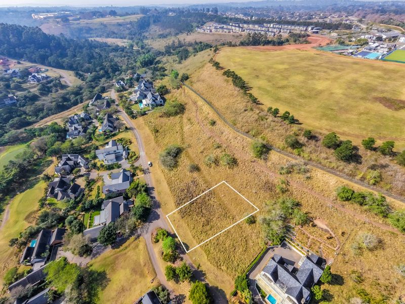 An aerial view of a vacant residential land plot situated within a developed estate, highlighting the site boundaries and surrounding neighborhood context.