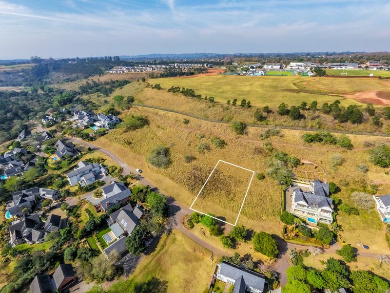 Aerial view of a vacant residential plot in a developed estate, showing the demarcated boundary and surrounding landscape.