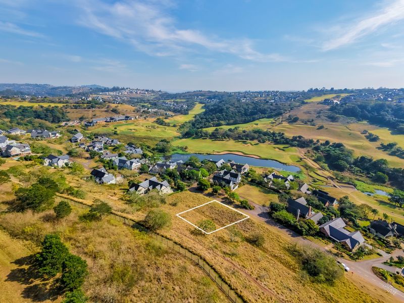 Aerial view of a vacant residential plot situated within a scenic estate, featuring surrounding greenery and established neighborhood infrastructure.