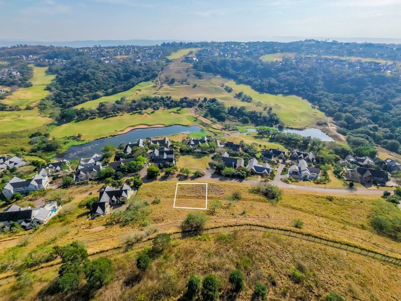 Aerial view of a vacant residential land plot situated within a scenic estate, featuring surrounding greenery and proximity to a golf course.