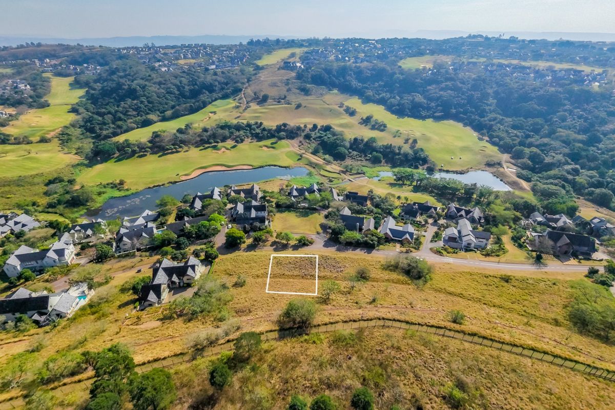 Aerial view of a vacant residential land plot situated within a scenic estate, featuring surrounding greenery and proximity to a golf course.